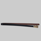 Black and brown belt with a gold buckle on a tiled floor